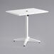 A white Lancaster Table & Seating outdoor table with a white powder-coated aluminum base and umbrella hole.
