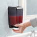 A hand using a San Jamar Black Pearl bulk soap dispenser.