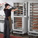 A woman in a bakery placing trays of pastries in a ServIt holding and proofing cabinet.