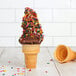 A chocolate ice cream cone with sprinkles filled with Rich's Plant-Based Chocolate Oat Milk soft serve.