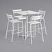 A white Lancaster Table & Seating bar height table with a hole in it and four white barstools.