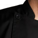 A close up of a black Chef Revival chef coat with black buttons.