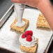 A person using a pastry bag to put Rich's On Top whipped marshmallow topping on square treats.