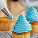 A person decorating a cupcake with Rich's Bettercreme blue whipped icing.