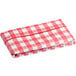 A red and white checkered vinyl table cover on a table with an umbrella opening.
