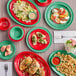 A table with plates of food, including green and red Acopa Foundations smooth melamine ramekins filled with sauce.