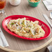 A red Acopa Foundations melamine oval platter with pasta and clams on it.