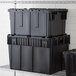 A stack of Lavex black stackable industrial totes.