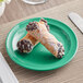 A close up of a chocolate covered cannoli on a green Acopa Foundations melamine plate.