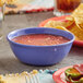 A purple melamine bowl of salsa and tortilla chips on a table.