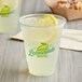 A cup of lemonade with ice and a lemon slice in a Carnival King PET lemonade cup.