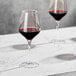 Two Della Luce Astro wine glasses filled with red wine on a marble table.