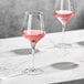Two Della Luce Astro wine glasses filled with pink liquid on a marble table.