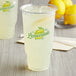 A close up of a Carnival King PET Lemonade Cup filled with lemonade on a table.
