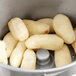 A close-up of white potatoes being peeled in an Avantco countertop potato peeler.