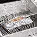 A food wrapped in Choice heavy-duty aluminum foil cooking on a grill.