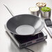 A Spring USA Slim-line induction range on a countertop with a frying pan and lid inside.