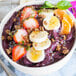 A bowl of purple smoothie with fruit and granola.