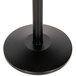 A black round base with a black pole on a table with a black marker board.