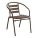 A brown metal Lancaster Table & Seating outdoor arm chair with a slatted back.
