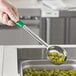 A hand holding a Choice green perforated portion spoon filled with green olives.