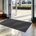A close-up of a large black Lavex Needle Rib indoor entrance mat.