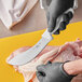 A person using a Choice curved skinning knife to cut meat.