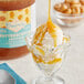 A glass cup with a scoop of Creamery Ave. Butterscotch Dessert Topping on ice cream.