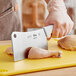 A person using a Choice 7" Cleaver with a white handle to cut chicken meat.
