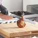 A person using a Choice 14" Smooth Edge Slicing Knife with a white handle to slice meat on a cutting board.