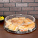 A Sabert clear plastic dome lid on a tray of sandwiches.
