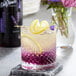 A glass of lavender-flavored drink with a lemon slice on the rim.