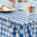 A table with a blue and white checkered tablecloth held in place with Choice stainless steel tablecloth clips.