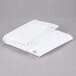 A stack of folded white Intedge vinyl table covers on a gray surface.