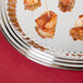 A Vollrath stainless steel oval fluted tray with bacon-wrapped shrimp on it.