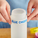 A person using blue and yellow silicone bands to label a squeeze bottle of blue cheese.