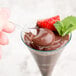 A Fineline clear plastic tasting spoon holding chocolate pudding with strawberries.
