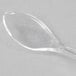 A close-up of a clear plastic Fineline Tiny Tasters tasting spoon.