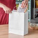 A person putting food in a white Choice shopping bag.