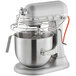 A silver KitchenAid countertop mixer with a wire bowl on top.