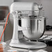A silver KitchenAid commercial mixer on a counter with a bowl.