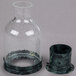A clear glass cylinder with a cup inside.