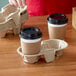 A hand holding two coffee cups in a Pulp Fiber cup holder.