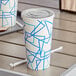 A white and blue Choice paper cold cup with a flat straw slot lid on a table.