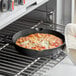 A person using Valor pre-seasoned cast iron skillet with dual handles to cook a pizza in an oven.