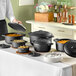 A group of Valor pre-seasoned cast iron pots and pans on a table in a professional kitchen.