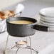 A Valor pre-seasoned cast iron fondue pot with liquid on top of a candle stand.