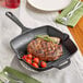 A Valor square cast iron grill pan with a steak and cherry tomatoes cooking inside.