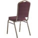 A Lancaster Table & Seating burgundy banquet chair with a gold metal frame.