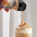 UPOURIA Cinnamon and Brown Sugar Shakeable Coffee Topping being sprinkled on a coffee drink.